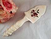 Ceramic serving spatula with ornate handle and floral design blade.