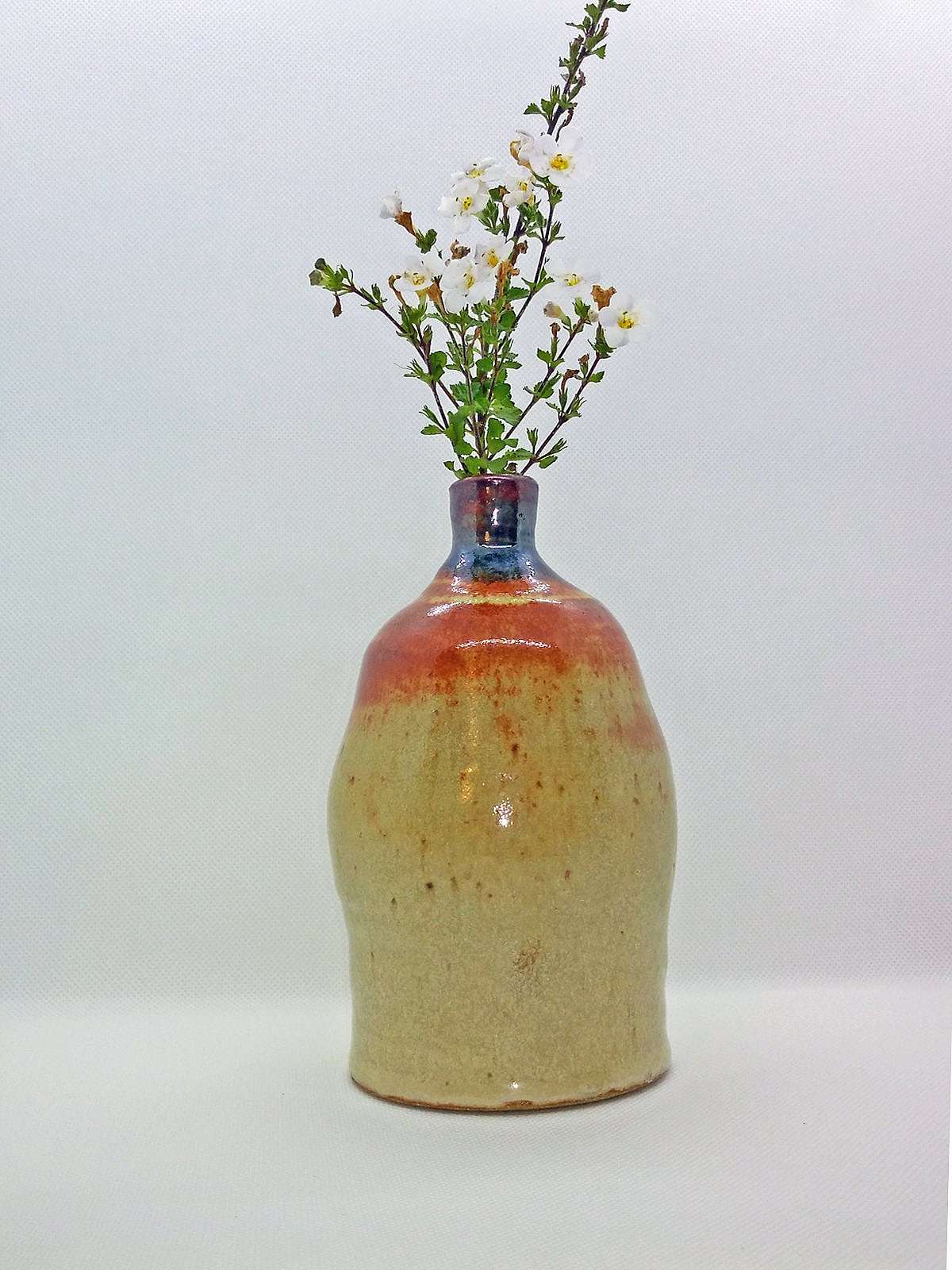 This is a beautiful studio art pottery vase with a beige undertone and brown and orange or brick colored drip glaze flowing from the top.  The opening is just 1/2" in diameter, perfect for a small plant or bud.  The piece weighs a sturdy one and a ha