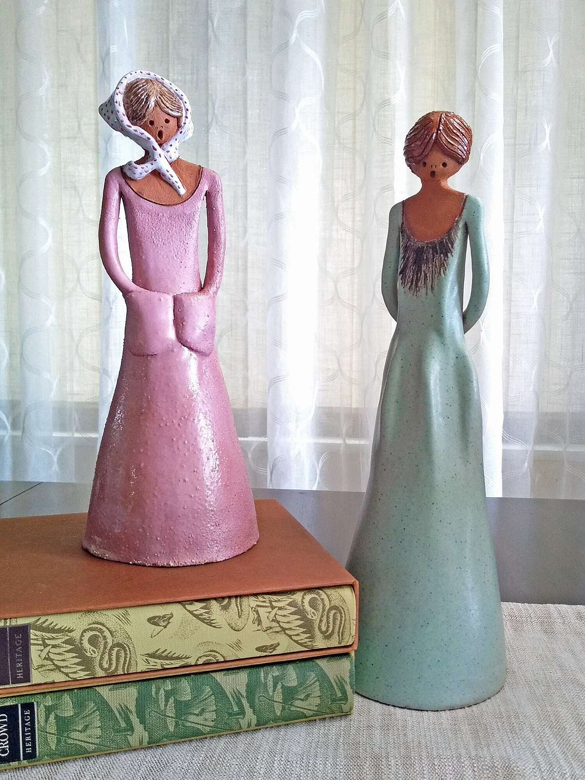 These two beautifully-painted artisan pottery young ladies are completely unique and original.  They seem to be young sisters, singing or chatting together.  Their fashion and hair-style is mid-1970's.   The older sister in a smooth dotted green dress h