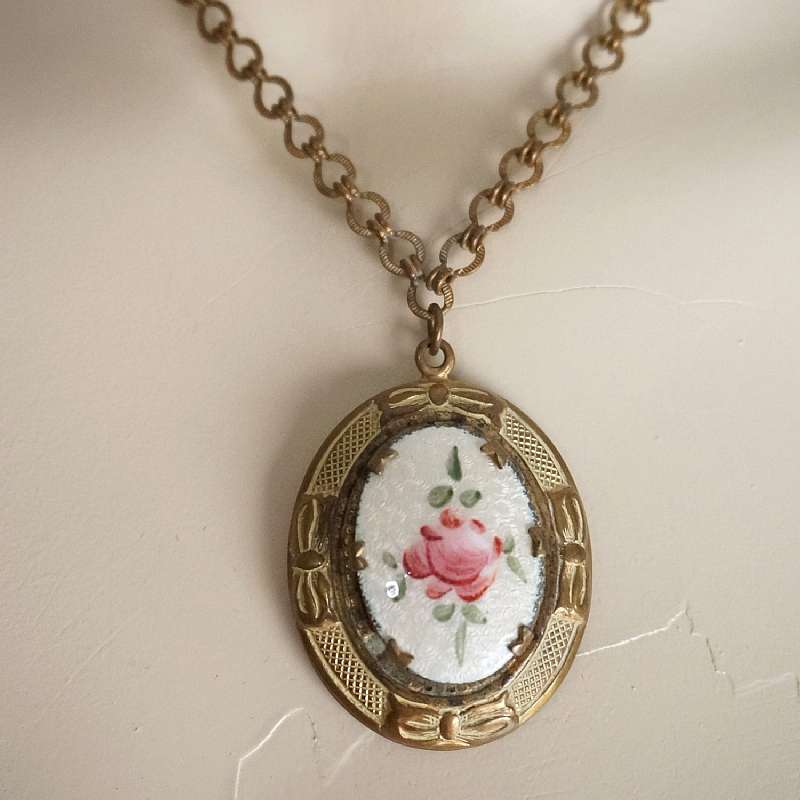 Gorgeous Art Nouveau vintage gilt brass guilloche enamel locket necklace. It had a lovely hand painted rose motif on guilloche enamel base with patterned bronze tone metal and bow accents. Measures 1 5/8 inches on the pendant and 16 inches on the unique p