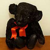 Fabulous antique vintage Teddy bear made from genuine lamb fur for the ultimate in luxury.  The bear is a jointed bear with gorgeous glass eyes, leather soles and a thick RED (my computer looks pumpkin) silk satin bow around his neck.  He measures 16 1/2