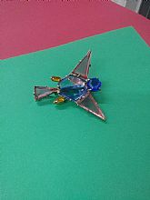 A metal bird with colored shapes to fill the metal and a blue rhinestone face